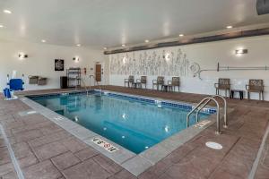富兰克林Sleep Inn & Suites Milwaukee-Franklin的一个带椅子和桌子的大型游泳池