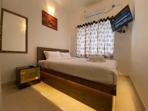 蓬蒂切里Le Poshe Luxury Pondicherry的一间卧室设有一张大床和一个窗户。