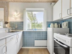 菲耶里茨莱乌Holiday Home Gisa - 500m from the sea in NW Jutland by Interhome的厨房铺有蓝色瓷砖,设有窗户。