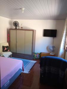 马卡埃Casa da Lu的一间卧室配有一张床和一台平面电视