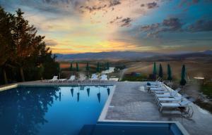 VillamagnaGlamping Diacceroni的一个带白色躺椅的游泳池,享有日落美景