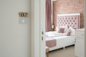 锡比乌Hotel Marabella的卧室配有白色床和粉红色床头板