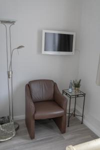 诺德奈Hotel Seehof Norderney OHG的墙上有电视的房间的棕色椅子
