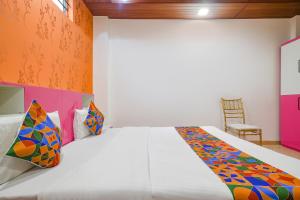 印多尔FabExpress Dream paradise的卧室配有一张带彩色枕头的大型白色床。