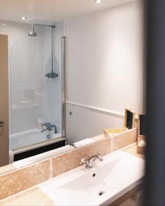 蒂贝Westmorland Hotel Tebay的浴室配有盥洗盆、镜子和浴缸