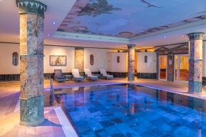 巴特埃姆斯Häcker's Hotel的一座带柱子和椅子的酒店游泳池
