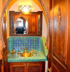 马拉喀什Riad Ghali Hotel & SPA的画画带水槽的浴室的人