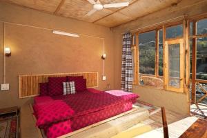 GushainiLiving Good - A Himalayan Boutique Stay的一间设有红色床的卧室,位于带窗户的房间内
