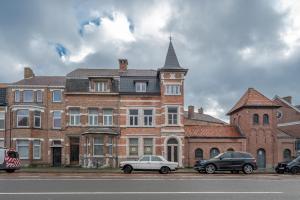 布鲁日Villa Cézar - big house at the center of Bruges - free parking的两辆汽车停在一座大型砖楼前