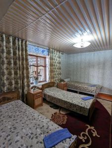 卡拉科尔Olzho Hostel的一间卧室设有两张床和窗户。