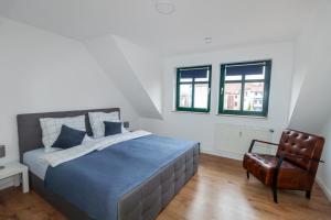 马格德堡Ferienwohnung "Kapellmeister" mit Klimaanlage in allen 4 Schlafbereichen, großes Wohnzimmer mit Smart TV und Big Sofa的一间卧室配有一张大床和一把椅子