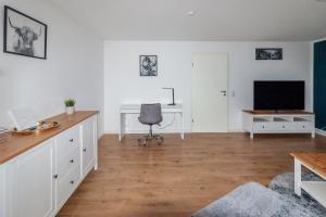 马格德堡Ferienwohnung "Kapellmeister" mit Klimaanlage in allen 4 Schlafbereichen, großes Wohnzimmer mit Smart TV und Big Sofa的客厅配有书桌和电视。