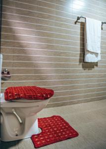 高尔阿里住宿加早餐旅馆的浴室设有卫生间,地板上铺有红色地毯。