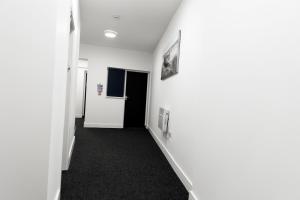 布赖尔利希尔Ledger Loft的走廊上设有白色墙壁和黑色地毯