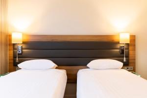 伦敦伦敦伊克赛尔慕奇夕酒店的配有白色床单的酒店客房内的两张床