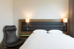 伦敦伦敦伊克赛尔慕奇夕酒店的一间卧室配有一张床和一张黑椅