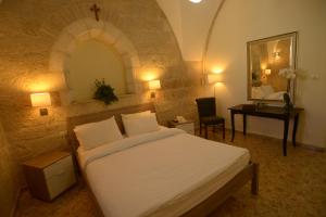 耶路撒冷耶路撒冷圣乔治大教堂朝圣旅馆的一间卧室配有一张床、一张书桌和一面镜子