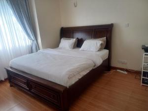Kitengela Amreff Nyumbani villas的卧室内的一张带白色床单和枕头的床