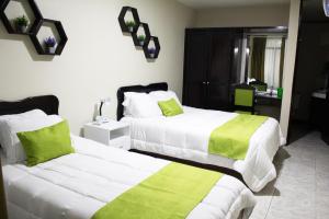 埃雷迪亚Hotel América Heredia的一间卧室配有两张带绿色和白色床单的床