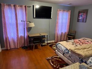 纽瓦克Guest House 3 BEDROOM 2 Bathrooms 5 MINS TO EWR NEWARK AIRPORT 4 MINS TO PENN STATION的一间卧室配有一张床、一张书桌和窗帘