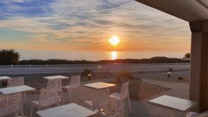 莱萨布勒-多洛讷拉维吉耶假期酒店的海洋上的日落,配有桌椅