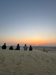 斋沙默尔Hostel Desert Home Stay的一群坐在海滩上的人,看着日落