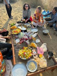 斋沙默尔Hostel Desert Home Stay的一群人坐在桌子旁吃着食物