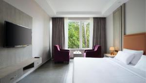 瓦加托The Porto by lagom , Anjuna, vagator beach的酒店客房配有一张床、两把椅子和一台电视