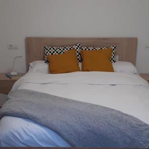 AhínL'Amagatall的一张白色大床,上面有橙色枕头