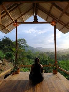 帕洛米诺La Mona Eco Cabins的坐在木甲板上欣赏山脉景色的女人