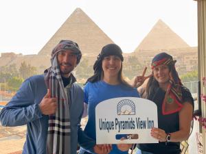 开罗Unique Pyramids View INN的一群人,在金字塔前拿着标志