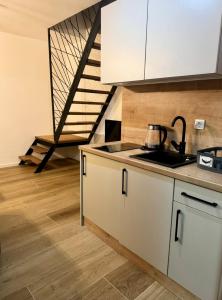 亚霍里纳Apartmani Andjela的厨房配有白色橱柜、水槽和楼梯。