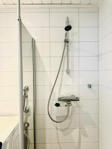 图尔库Turku Central Luxury Modern Cozy Flat 69m2的白色瓷砖浴室内带软管的淋浴