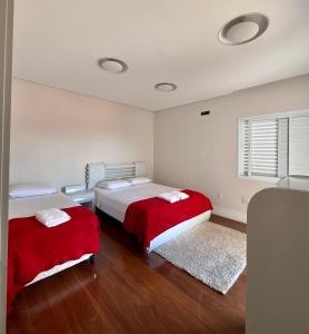 索科罗Casa alto padrão em Socorro的一间卧室配有两张红色床罩