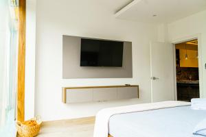 瓜亚基尔Luxury Apartments estilo New York的一间白色卧室,墙上配有电视