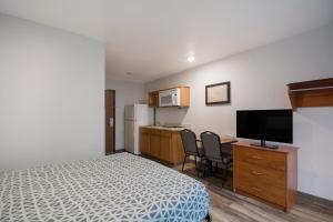 奥古斯塔WoodSpring Suites Augusta Riverwatch的一间卧室配有一张床和一张书桌及电视