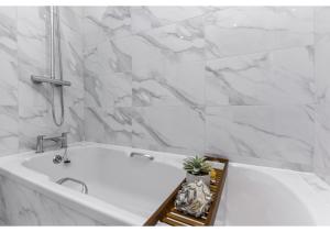 伦敦Modern Comforts 2 BD Flat - Sleeps 5的设有带白色浴缸的大理石墙浴室