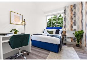 伦敦Modern Comforts 2 BD Flat - Sleeps 5的一间卧室配有一张床、一张桌子和一把椅子