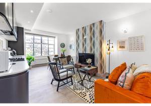 伦敦Modern Comforts 2 BD Flat - Sleeps 5的客厅配有橙色沙发和椅子