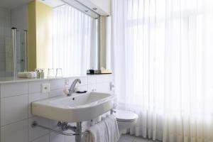 因特拉肯Grand Hotel Beau Rivage Interlaken的一间带水槽、卫生间和镜子的浴室