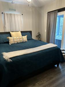 新布朗费尔斯Creed's Cottage at Four Oaks的一间卧室配有一张带蓝色毯子的床和窗户。