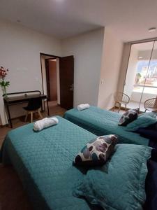 科恰班巴Un lugar para ti en Cochabamba.的一间卧室配有两张带枕头和钢琴的床