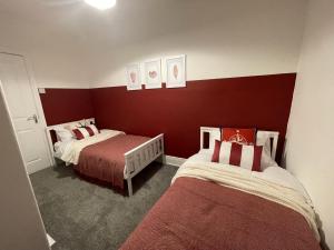 滨海纽比金Château by the Sea - Luxury hotel style 3 bed with hot tub的红色墙壁客房的两张床