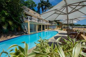 布希奥斯Pousada e Spa Villa Mercedes by Latitud Hoteles的一个带遮阳伞的室外游泳池和一个度假村