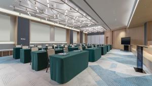 中山EVEN Hotel 中山中心逸衡酒店的一间会议室,配有绿色的桌椅
