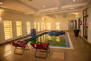 OnitshaAbada Luxury Hotel and Suites的一座带两把椅子的房子内的游泳池