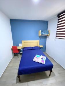 普埃布拉Hostal Talavera的蓝色的客房配有一张床和一张桌子