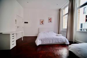 布鲁塞尔Smart Appart - Bossaerts的一间卧室配有一张床、一个梳妆台和两个窗户。