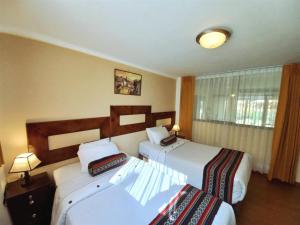 奥兰太坦波Hotel Humantay Lodge Ollantaytambo的酒店客房设有两张床和窗户。