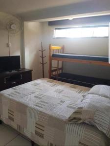 瓜拉图巴Apartamentos na Quadra do Mar的一间卧室配有一张床、一台电视和一个窗口